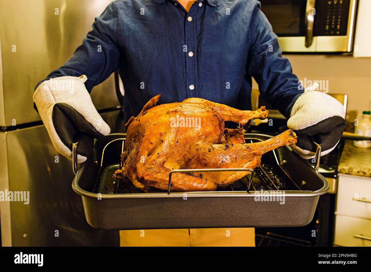 Ein Mann, der ein Tablett mit gebratenem, knusprigem truthahn hält, und Thanksgiving-Essen zubereitet Stockfoto