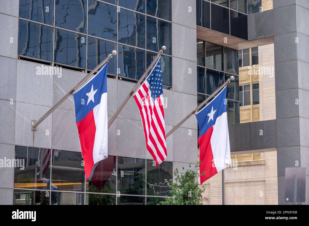 Amerikanische und texanische Flaggen auf dem Bürogebäude in der Innenstadt von Houston. Stockfoto