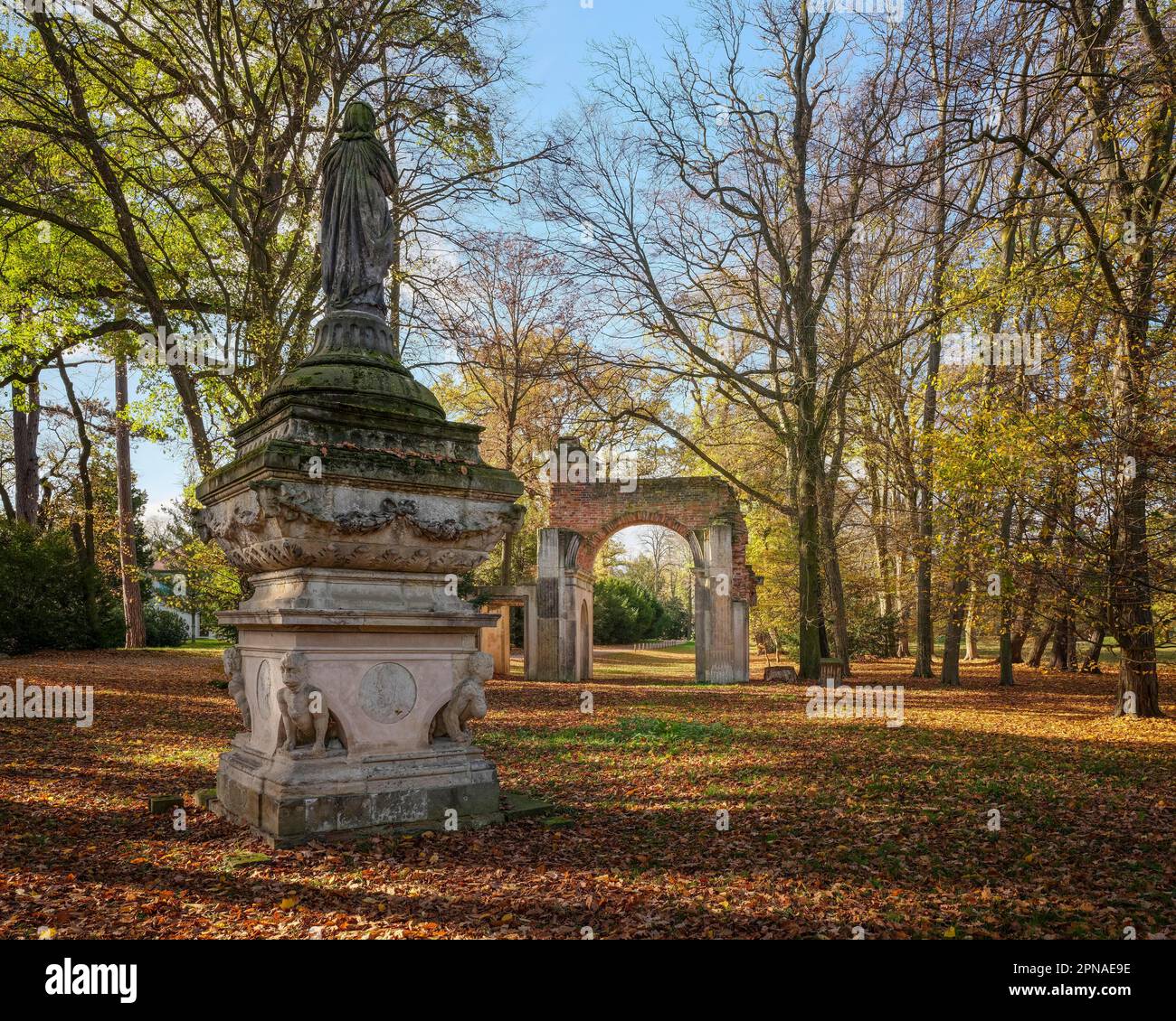 Skulptur des verschleierten Bildes von Sais und der römischen Ruine Arch im Luisium Park im Herbst, Dessau-Woerlitz Garten, UNESCO-Weltkulturerbe Stockfoto