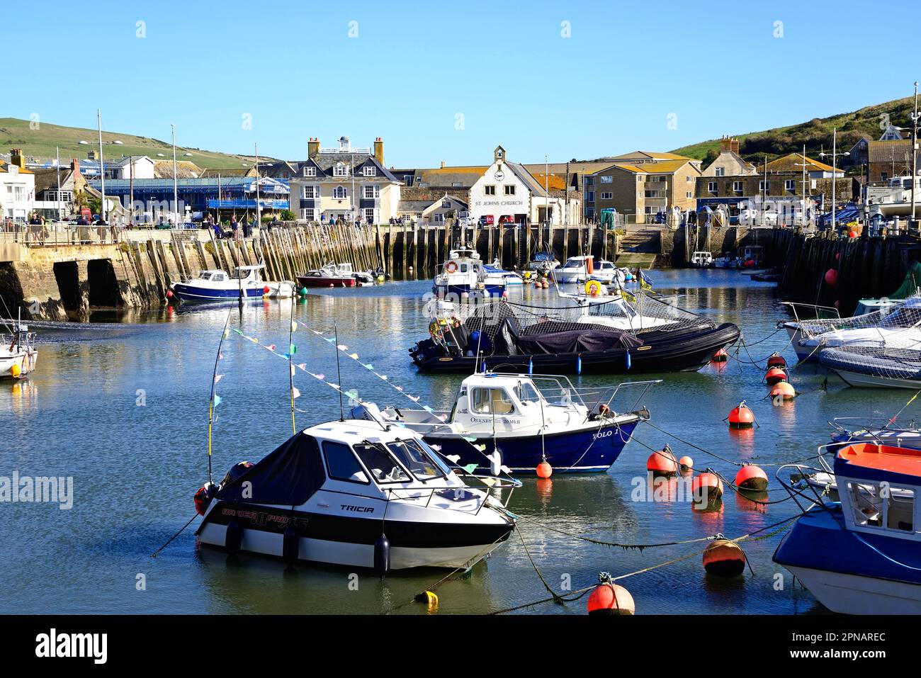 Fischerboote im Hafen mit Stadtgebäuden hinten, West Bay, Dorset, Großbritannien, Europa. Stockfoto