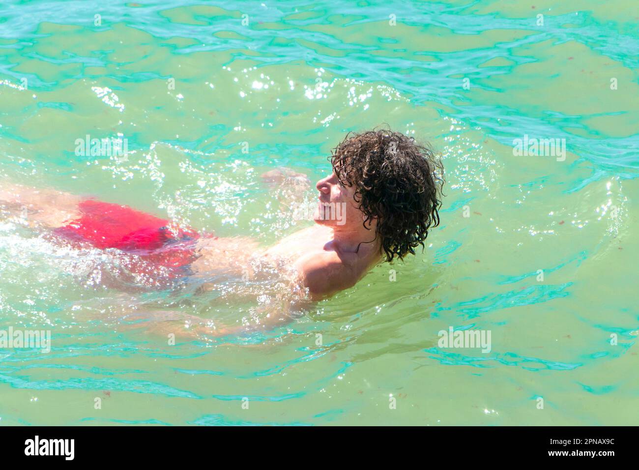 Ein Teenager in Badehosen schwimmt auf dem Rücken, nachdem er in albufeira an der algarve portugal ins Meer gesprungen ist Stockfoto