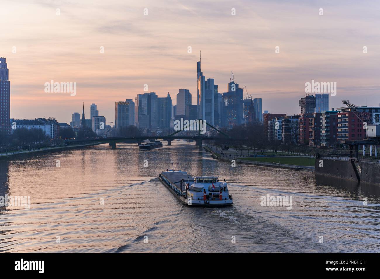 Ein Hochseeschiff, das vor einer modernen und belebten Skyline in Frankfurt segelt Stockfoto