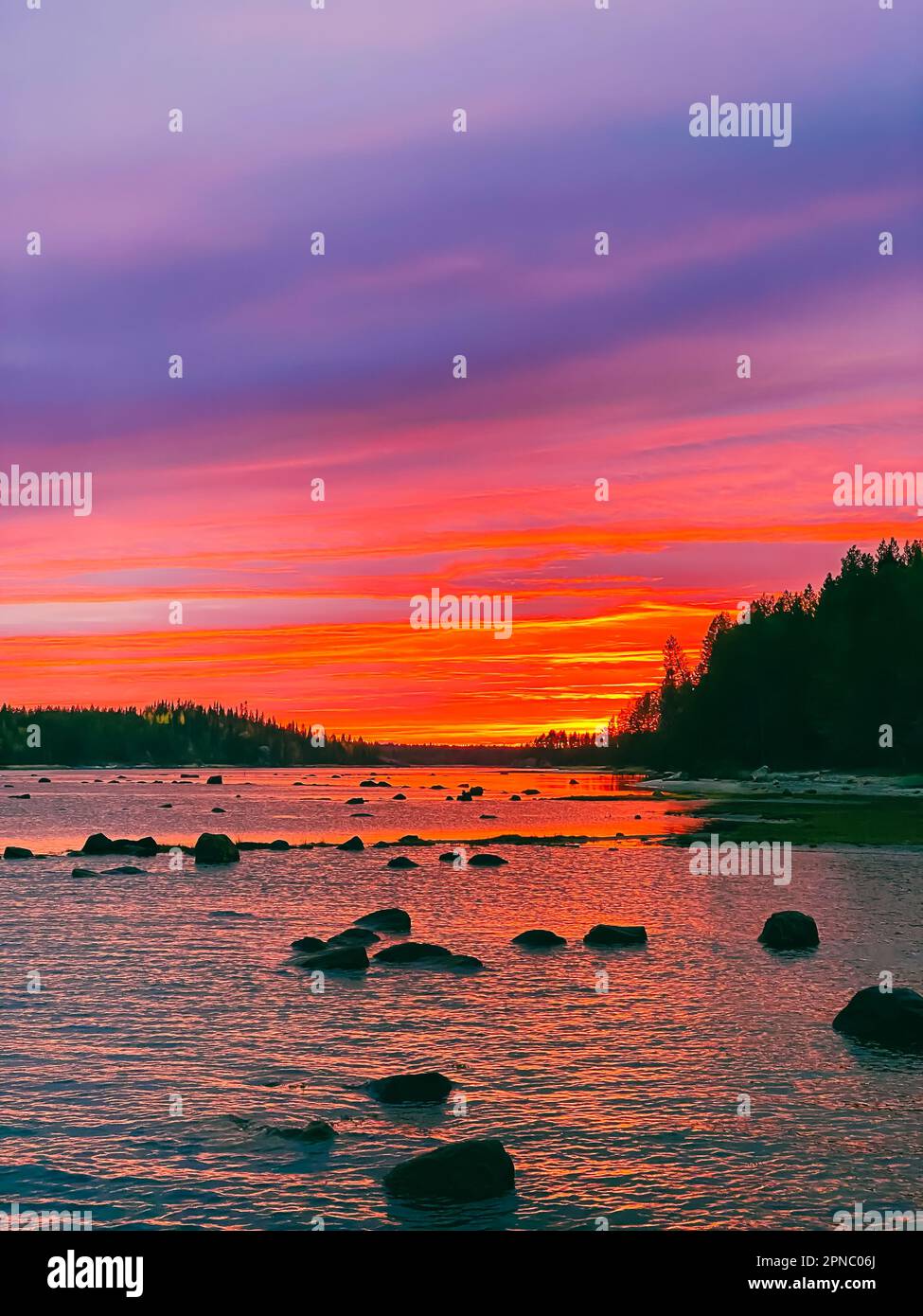 Wunderschöner heller, farbenfroher Sonnenuntergang über der Meeresbucht bei Ebbe Stockfoto