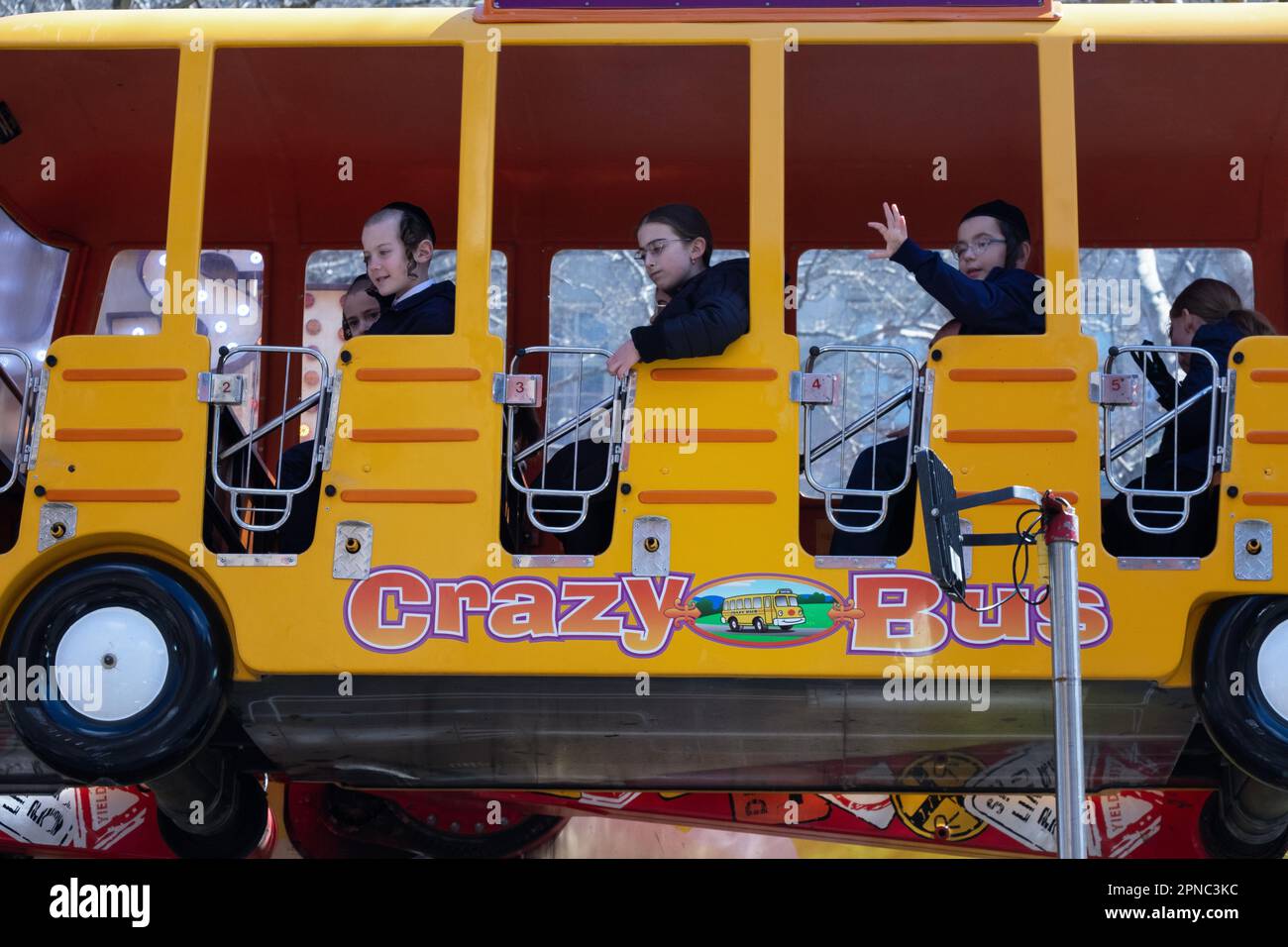 Während des Passover, wenn es zum Spaß verpflichtet ist, fahren chasidische Kinder mit dem Crazy Bus in einem temporären Vergnügungspark im Freien in Williamsburg, Brooklyn, N Stockfoto