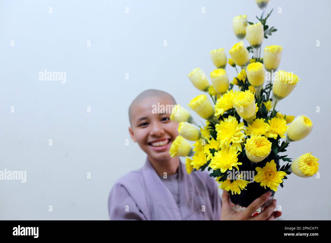Thien Quang Co TU buddhistischer Tempel. Lächelnde buddhistische Nonne mit gelben Blumen. Tan Chau. Vietnam. Stockfoto