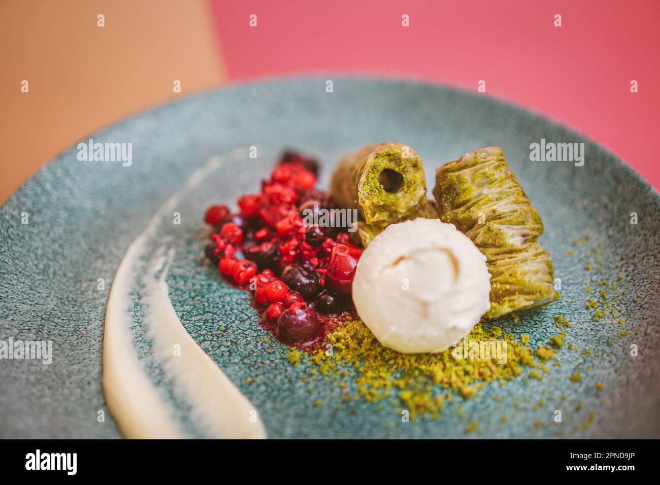 Nahaufnahme von Pistazienbaklava mit Vanilleeis und frischen Beeren, ein Gourmet-mediterranes Dessert für besondere Anlässe Stockfoto