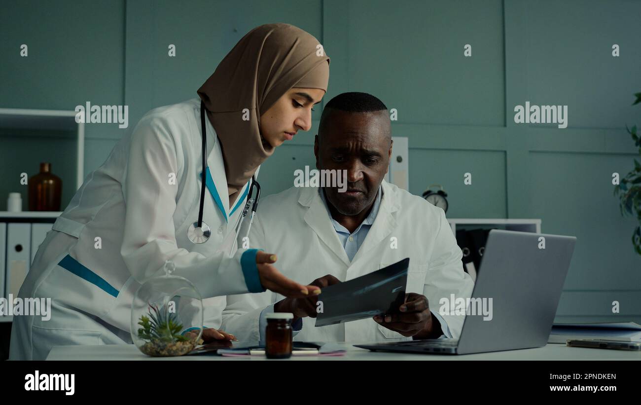 Multirassenärzte Kollegen diskutieren Teamarbeit afrikanischer Mann und arabische Frau zwei professionelle medizinische Arbeiter sprechen über Healthcare Check MRT-Scan Stockfoto