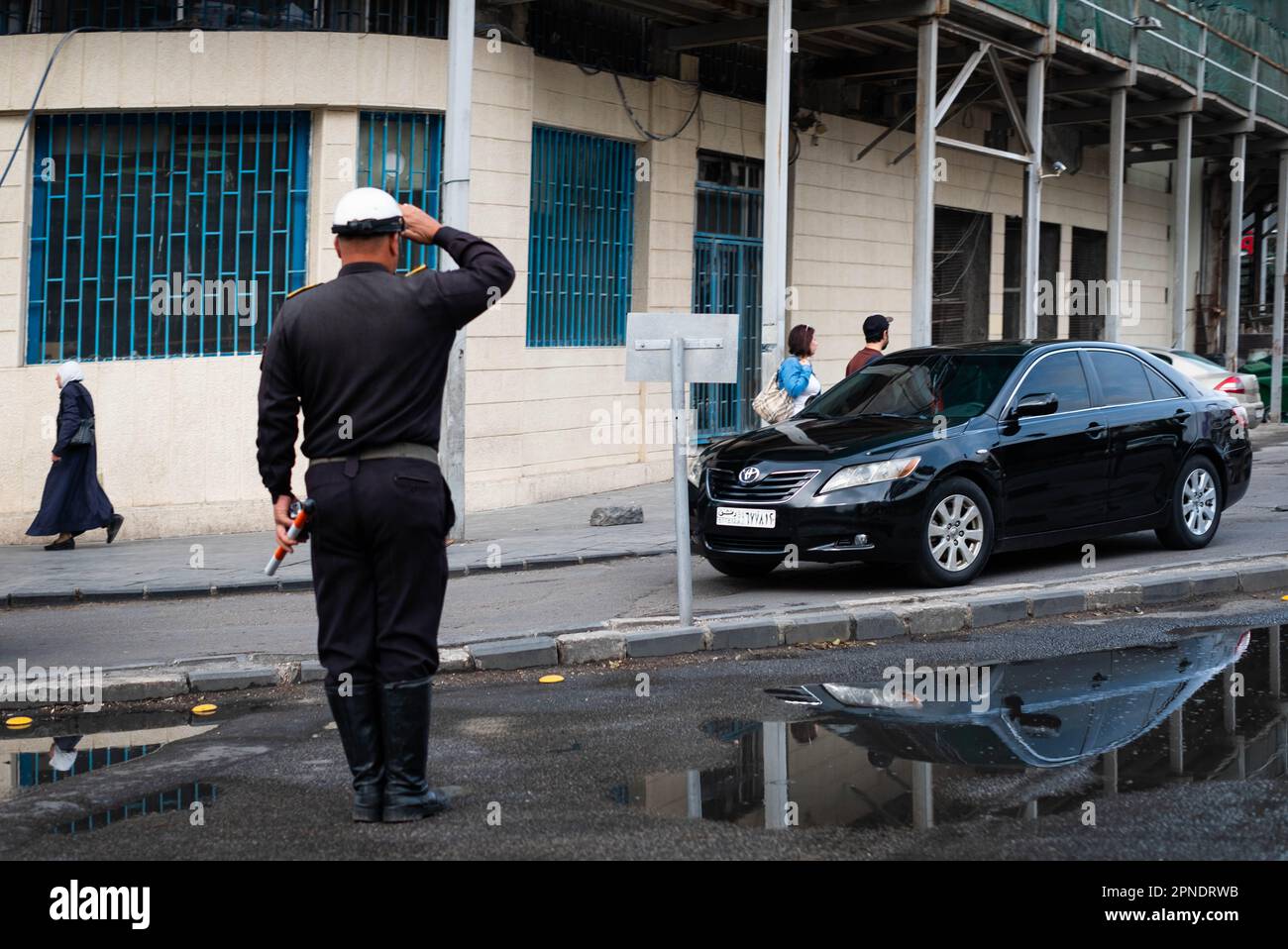 Damaskus, Syrien - April 2023: Polizeibeamter salutiert einem vorbeifahrenden Auto in Damaskus, Syrien Stockfoto