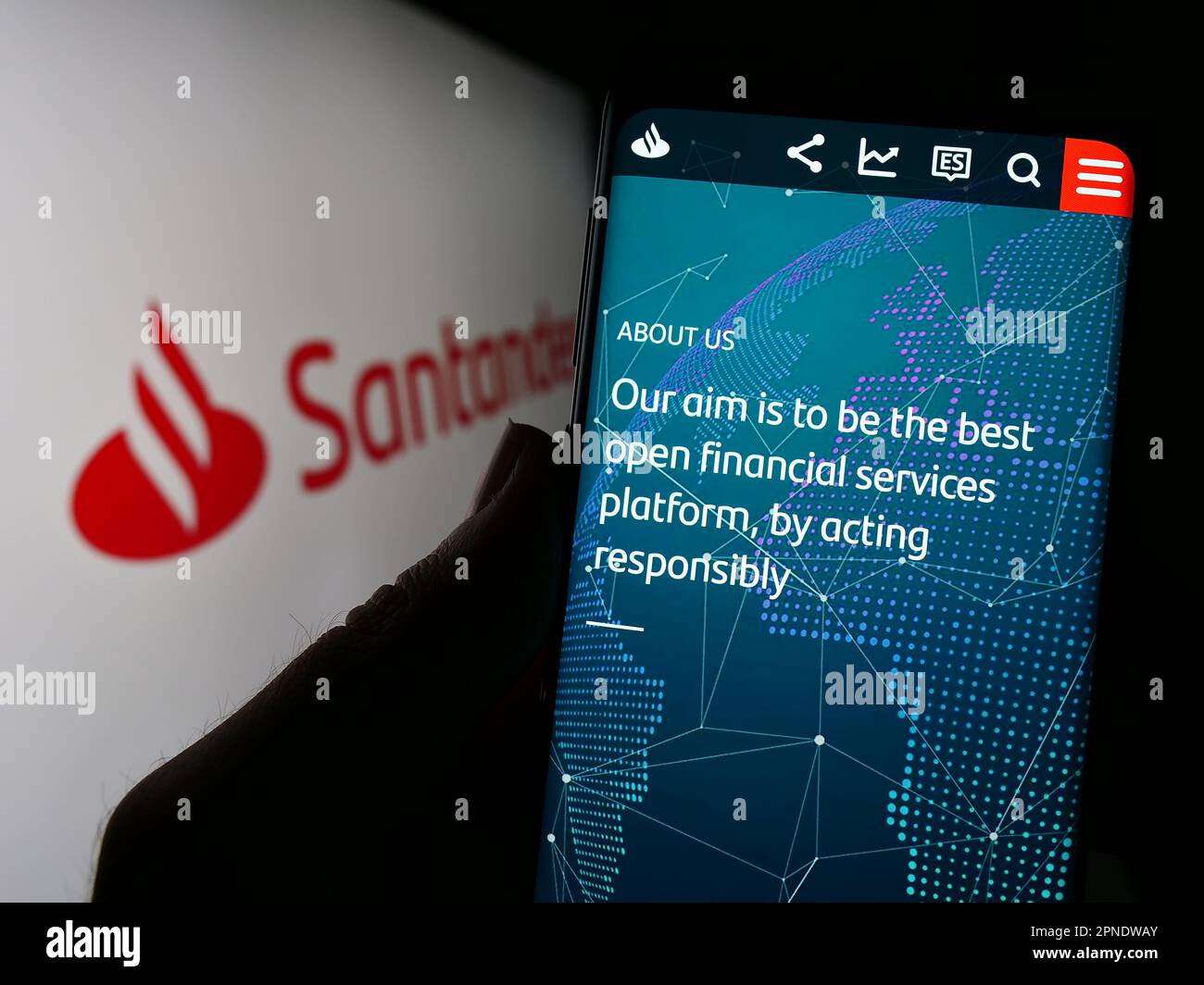 Person, die ein Mobiltelefon mit einer Webseite des spanischen Bankunternehmens Banco Santander SA auf dem Bildschirm vor dem Logo hält. Konzentrieren Sie sich auf die Mitte des Telefondisplays. Stockfoto