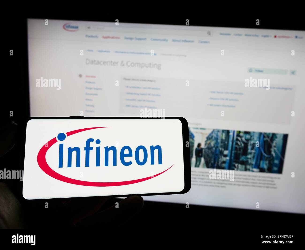 Person, die ein Smartphone mit dem Logo des Halbleiterunternehmens Infineon Technologies AG auf dem Bildschirm vor der Website hält. Konzentrieren Sie sich auf das Display des Telefons. Stockfoto