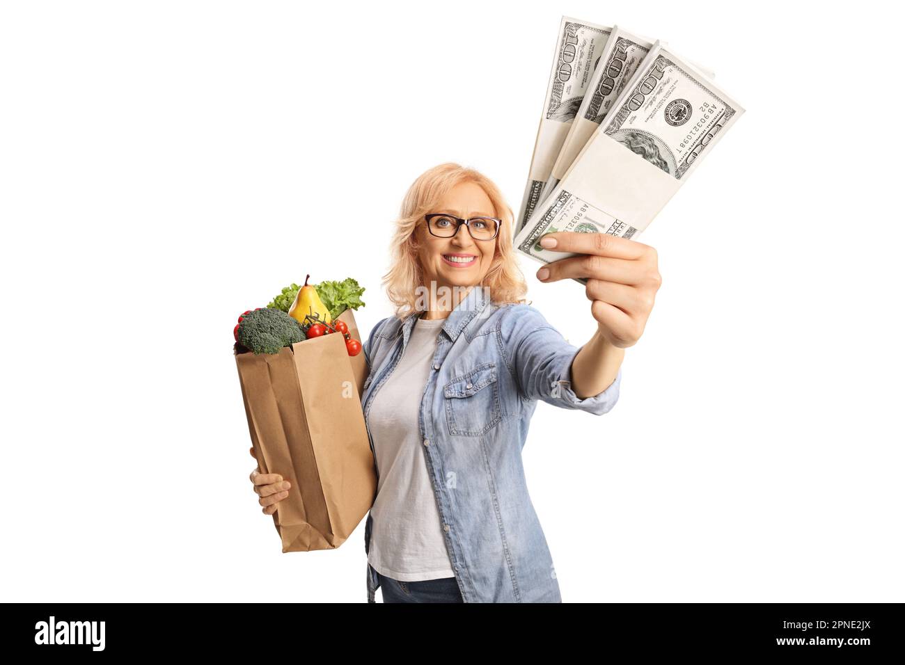Eine Frau mit einer Einkaufstasche, die lächelt und Geldstapel zeigt, isoliert auf weißem Hintergrund Stockfoto