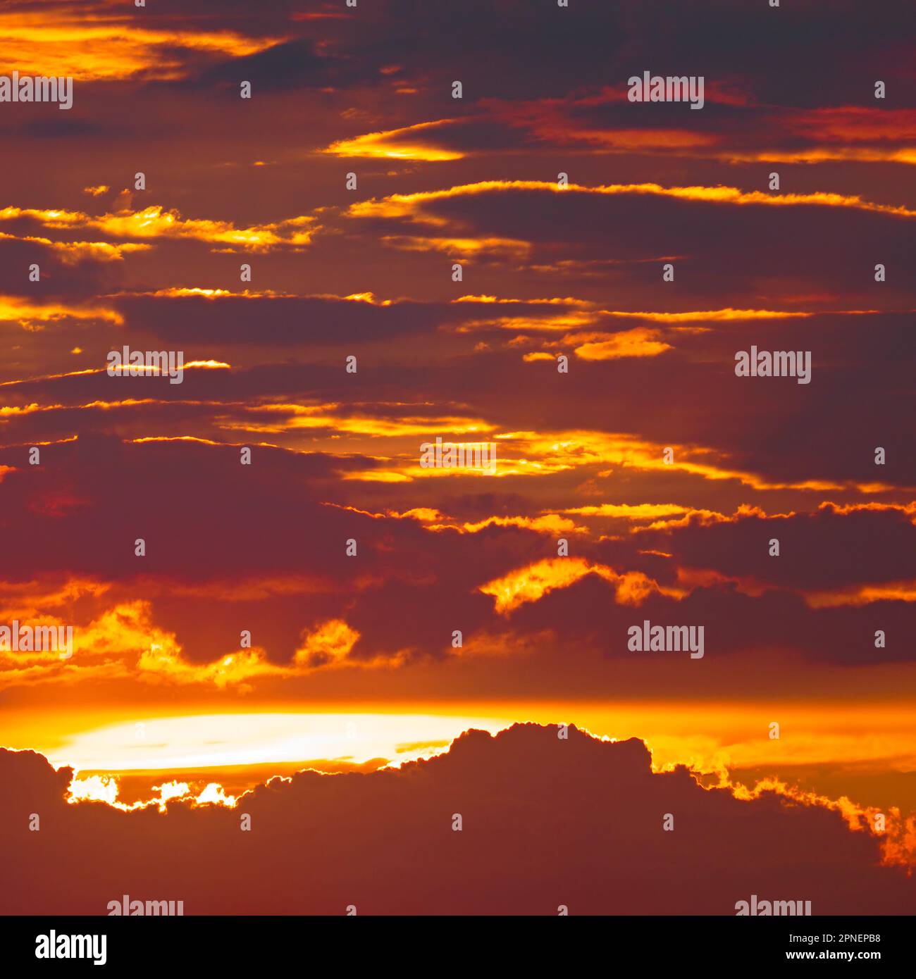Helle Sonne vor dunklen Wolken und rotem Himmel Stockfoto