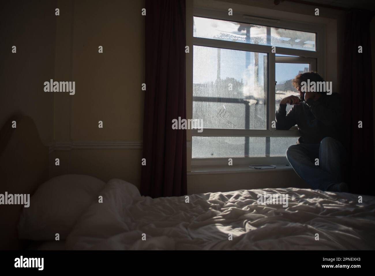 Ein Mann verdampft vor seinem Hotelzimmerfenster in einem südbritischen Hotel Folksteone. Bild aufgenommen im Grand Burstin Hotel, Teil von Britannia Hotels, Folkstone Stockfoto