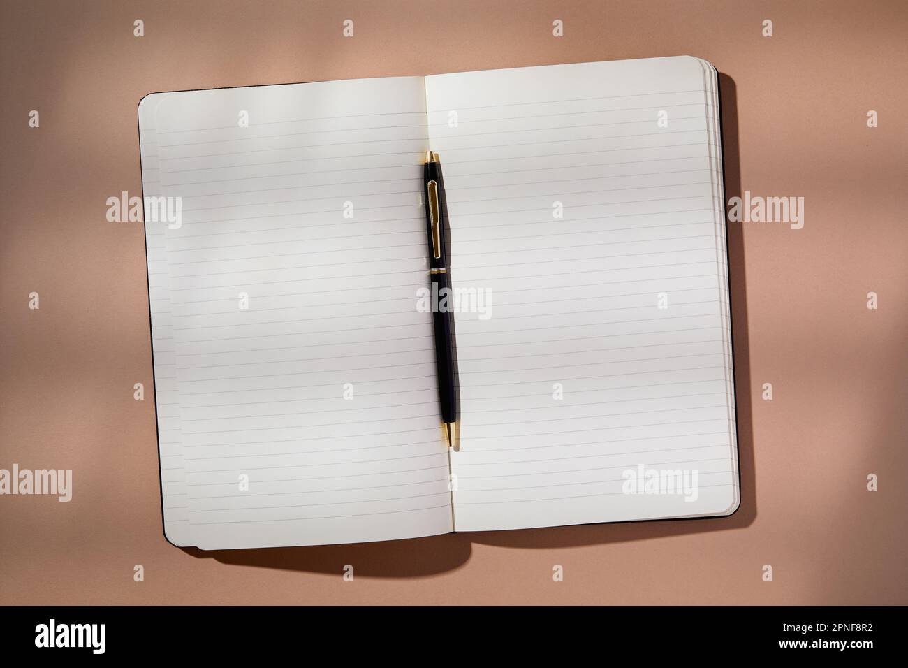 Stift in offenem Notizbuch auf braunem Hintergrund Stockfoto
