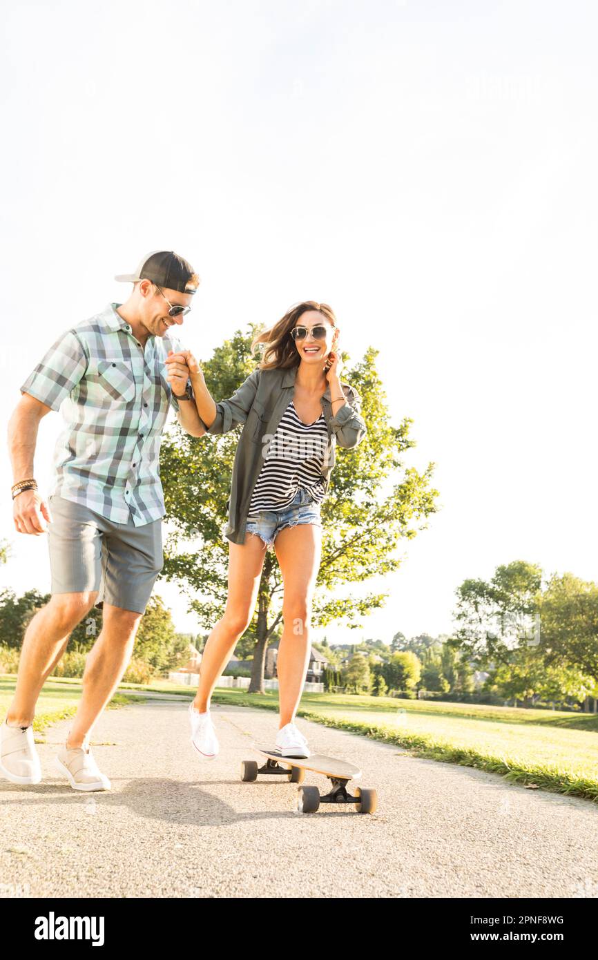 Ein Mann, der eine Frau auf dem Longboard hält Stockfoto