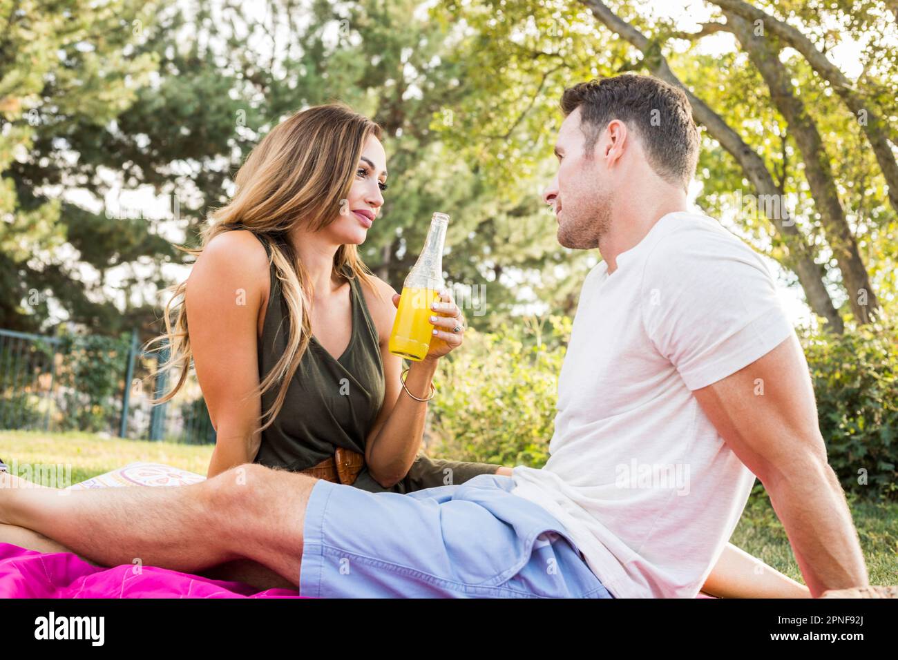Ein Paar, das auf einer Decke sitzt und sich beim Picknick im Park unterhält Stockfoto