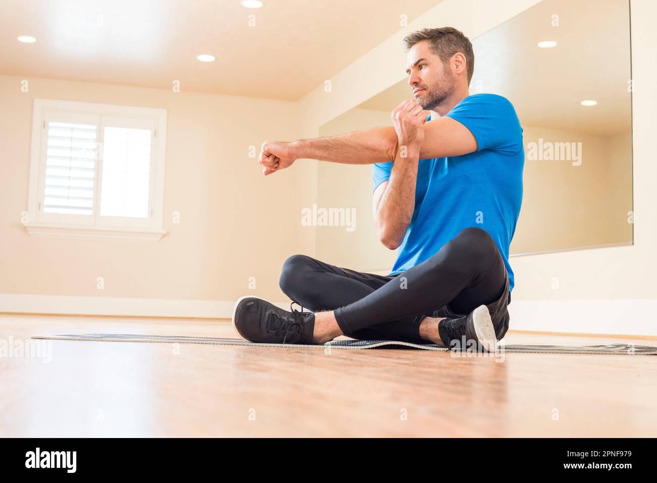 Mann sitzt auf dem Boden und streckt den Arm Stockfoto