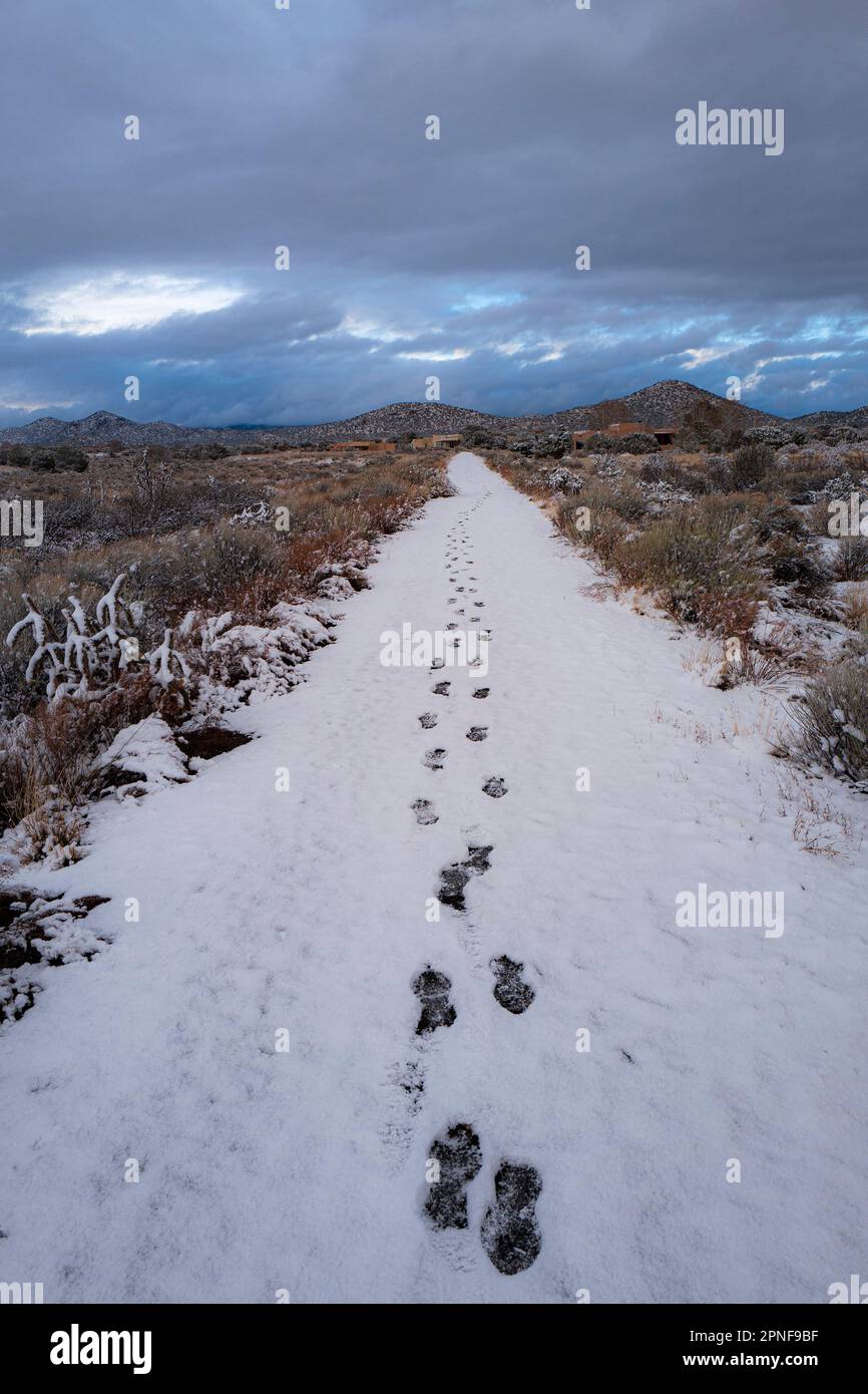 USA, New Mexico, Santa Fe, Fußspuren im Schnee unter bewölktem Himmel Stockfoto