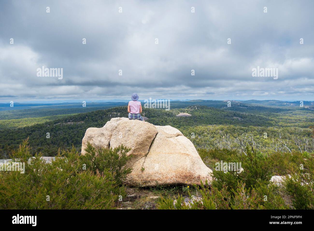 Australien, New South Wales, bald Rock National Park, eine Frau, die auf einem Felsen sitzt und sich umsieht Stockfoto