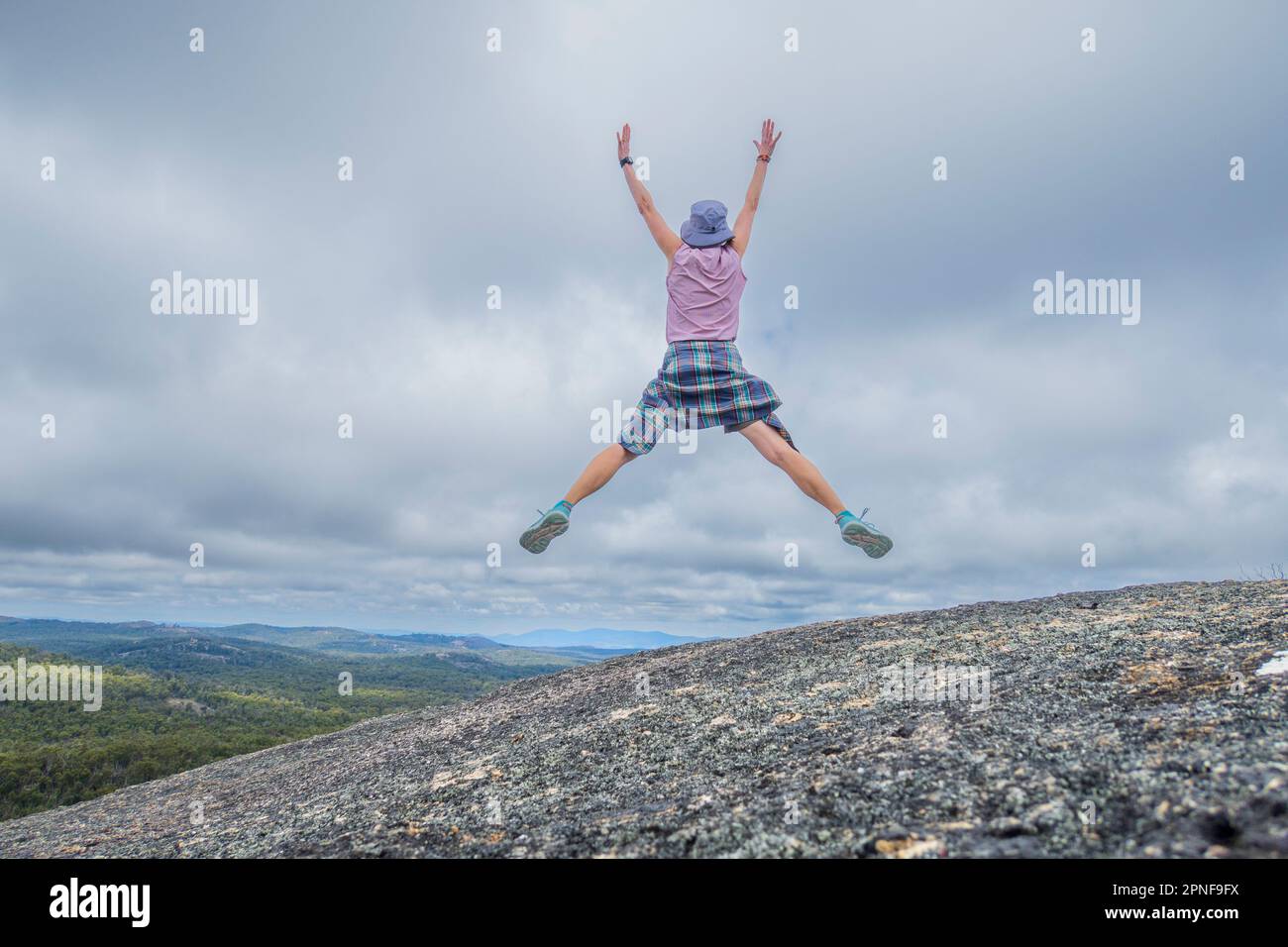Australien, New South Wales, bald Rock National Park, eine Frau, die mit erhobenen Händen im Freien aufspringt Stockfoto