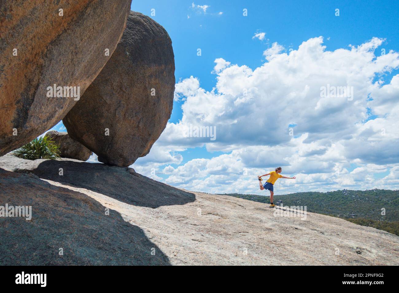 Australien, Queensland, Girraween-Nationalpark, Mann beim Sport neben dem großen Felsbrocken Stockfoto