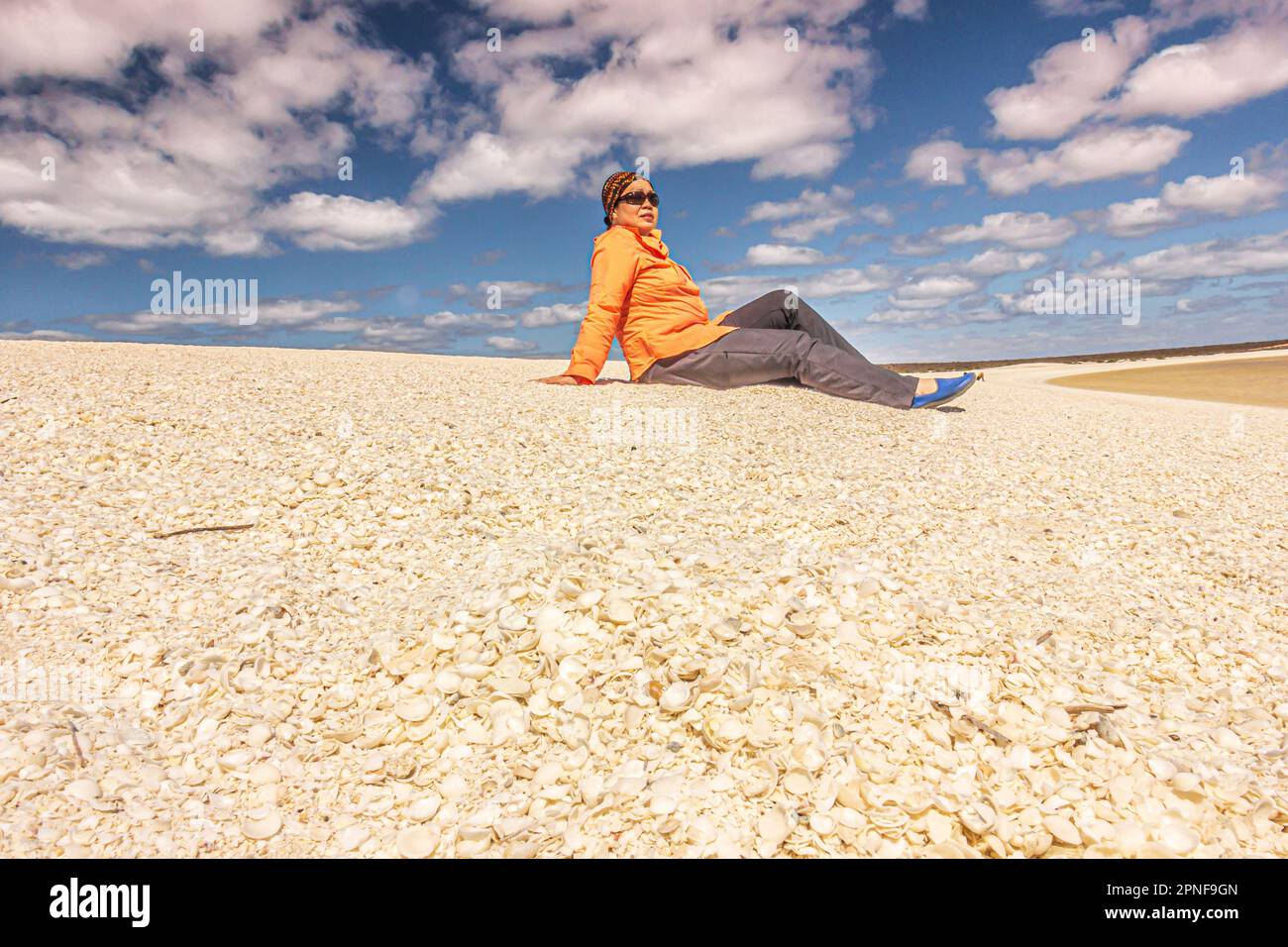 Eine Frau sitzt entspannt auf einem Haufen Muscheln am Shell Beach in der Shark Bay Region in Westaustralien, Australien. Stockfoto