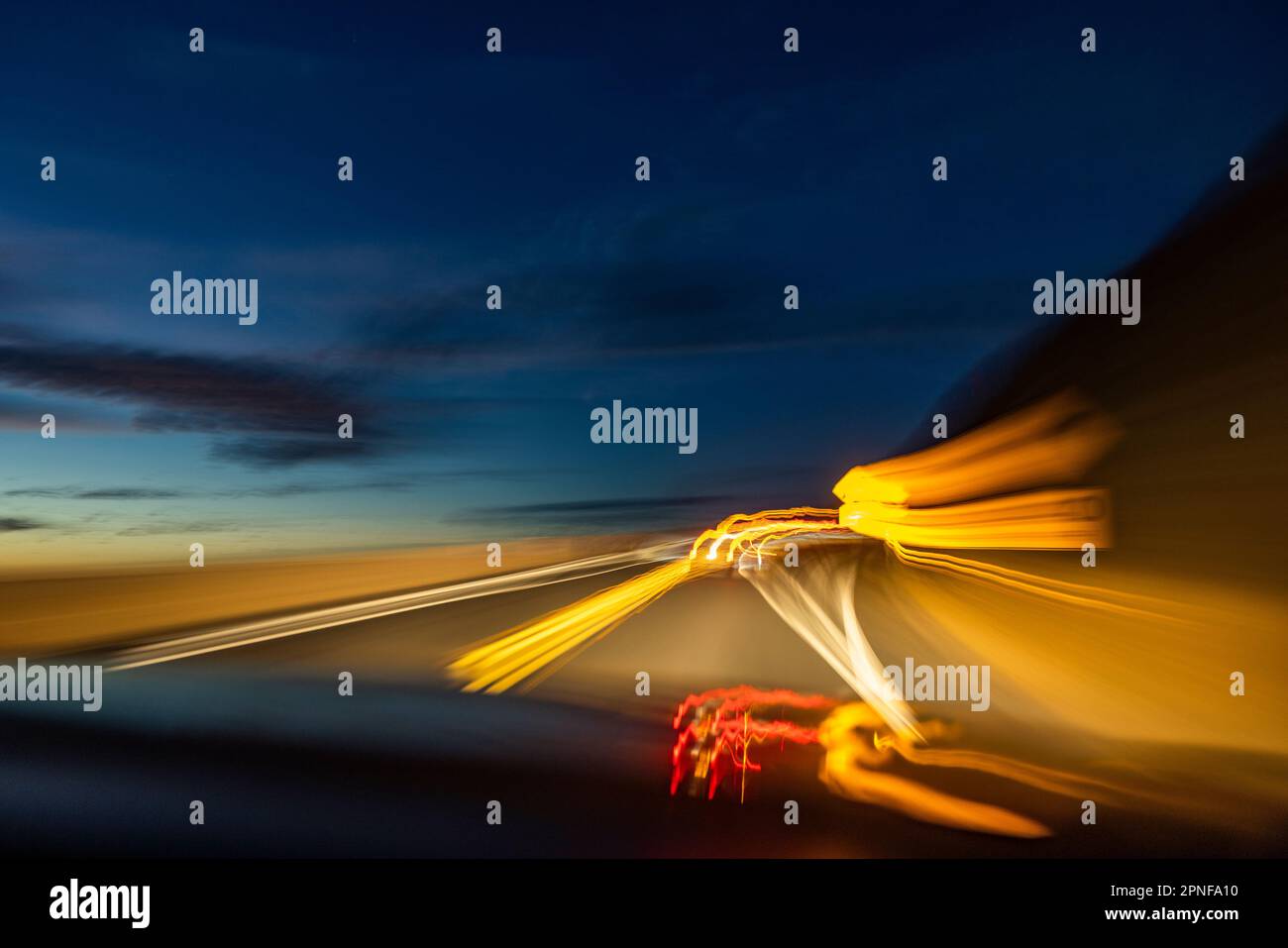 Verschwommenes Bild von Lichtern auf der Autobahn in der Dämmerung Stockfoto