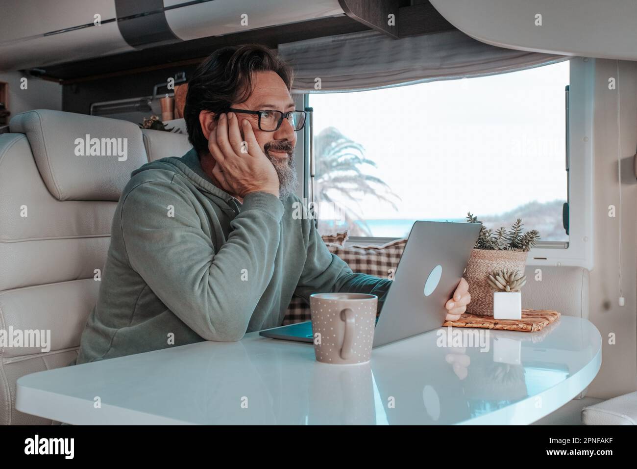Mann, der im mobilen Zuhause sitzt und an einem Laptop arbeitet Stockfoto