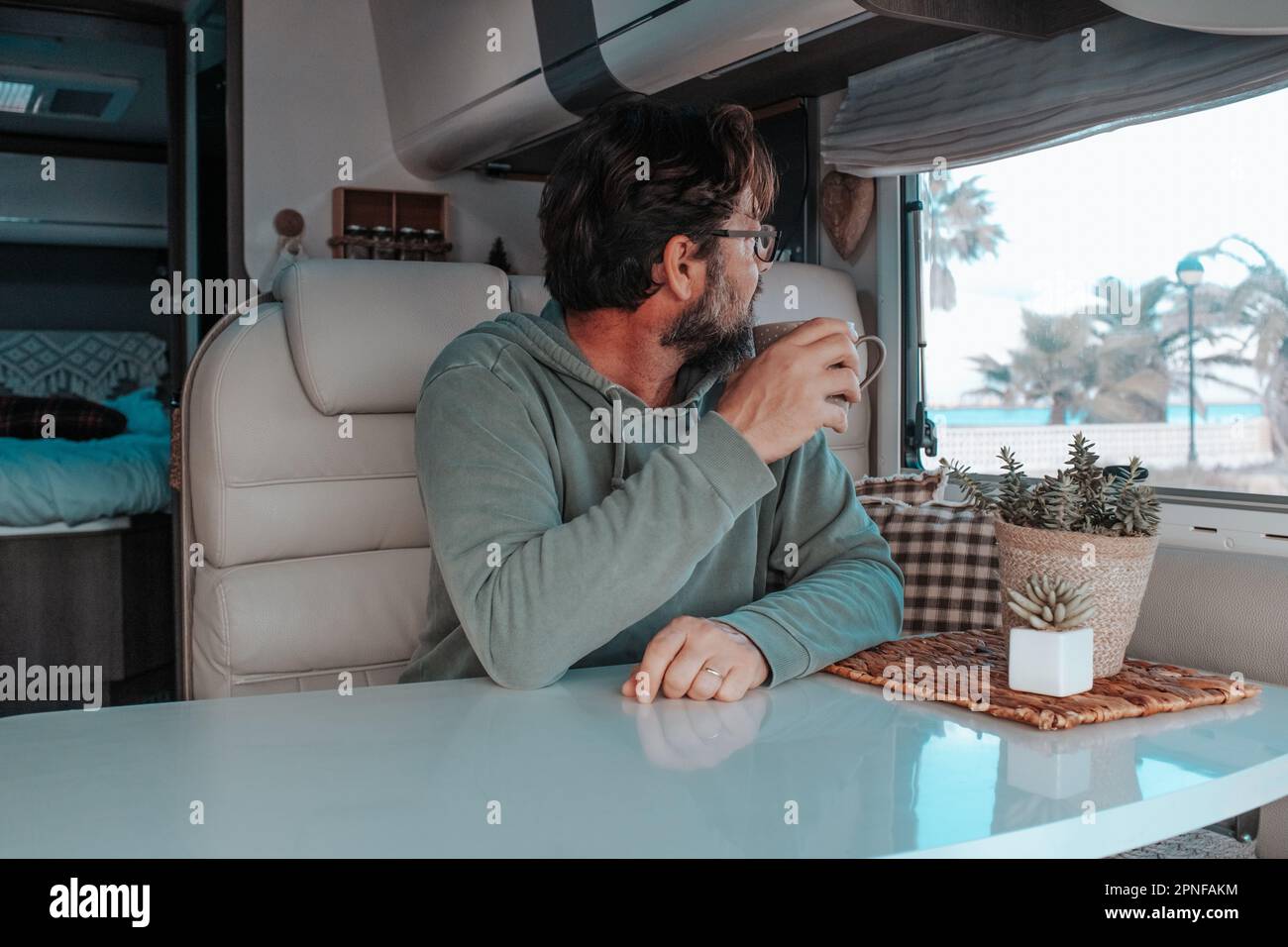 Mann sitzt im Wohnmobil und trinkt Tee Stockfoto