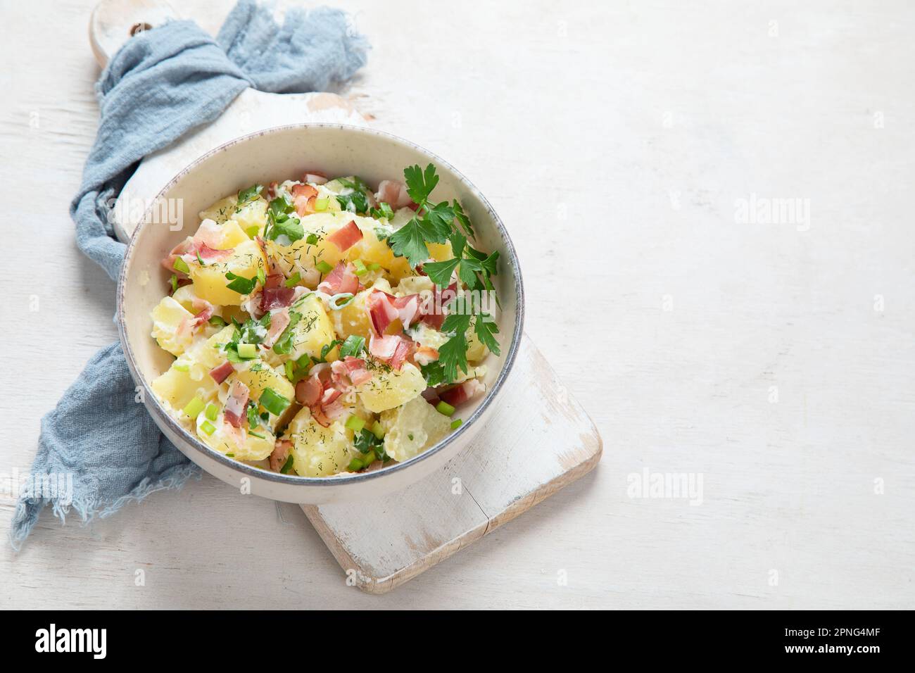 Schüssel mit warmem Kartoffelsalat mit Speck auf weißem Hintergrund. Draufsicht. Speicherplatz kopieren. Stockfoto