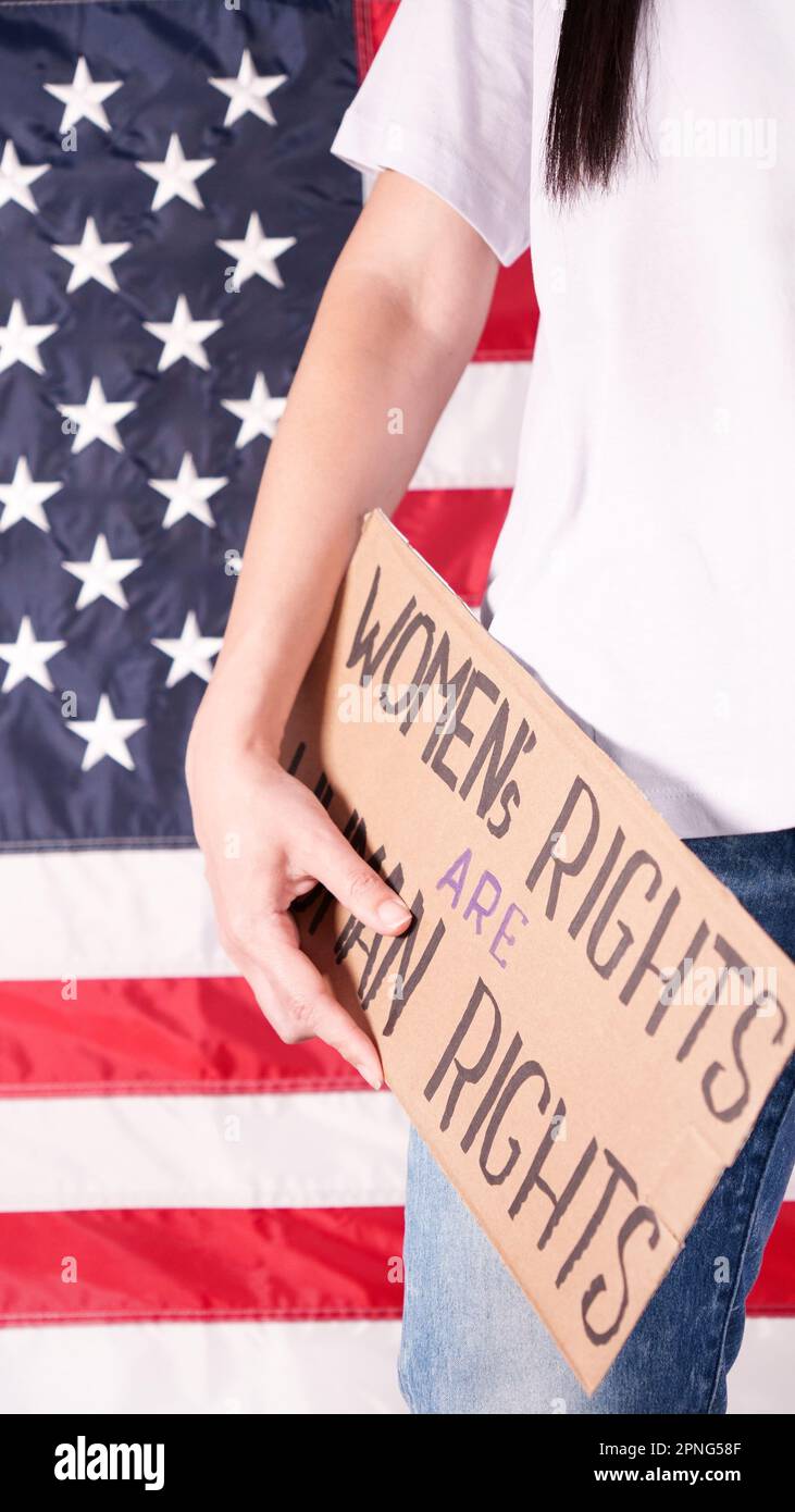 Frau hält ein Schild Frauenrechte sind Menschenrechte US-Flagge auf dem Hintergrund. Protest gegen Abtreibungsverbot. Frauenstreik. Frauen Rechte Freiheit Stockfoto