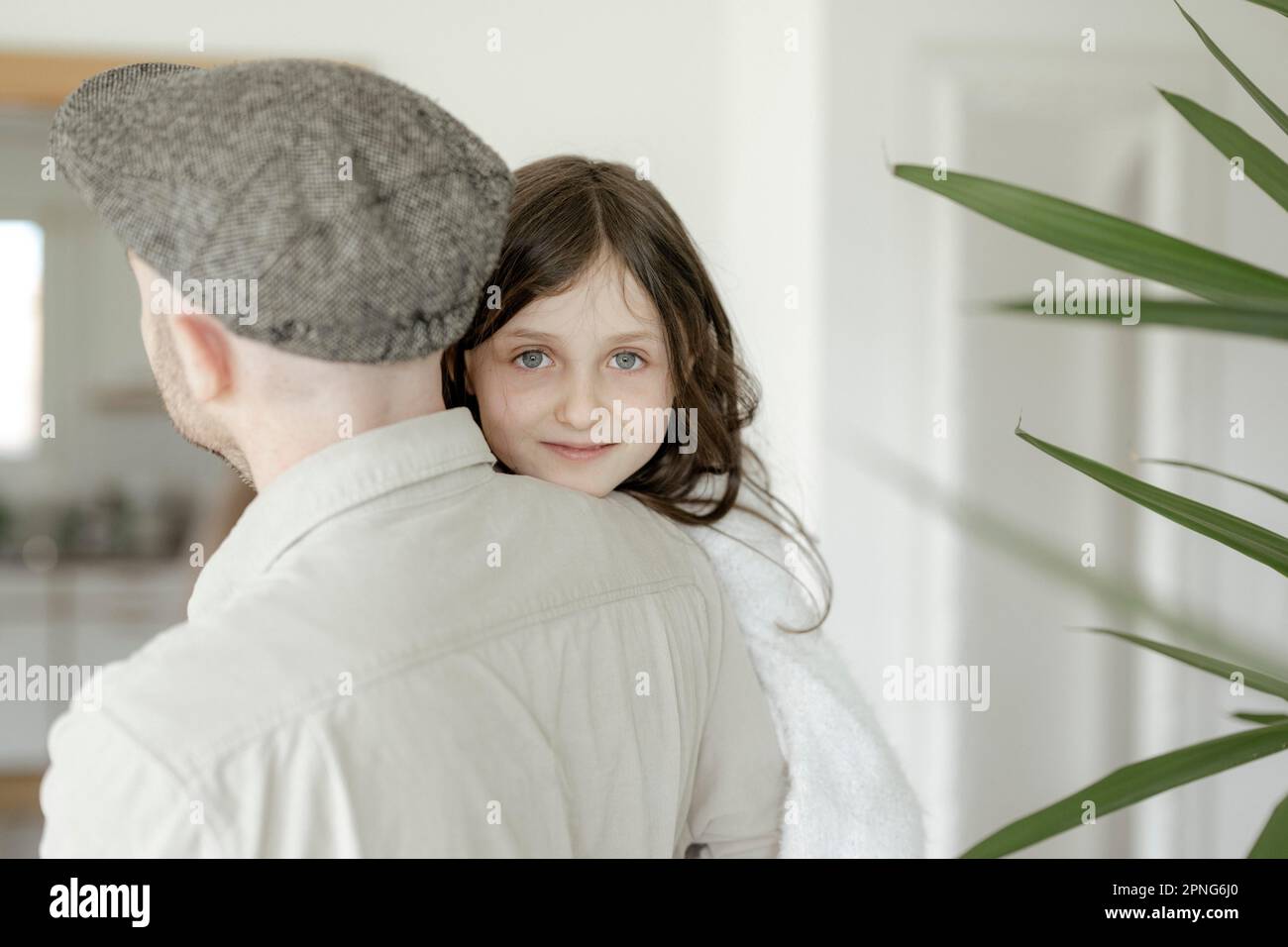 Mädchen, 8 Jahre, lächelnd, blickte über Daddys Schulter Stockfoto