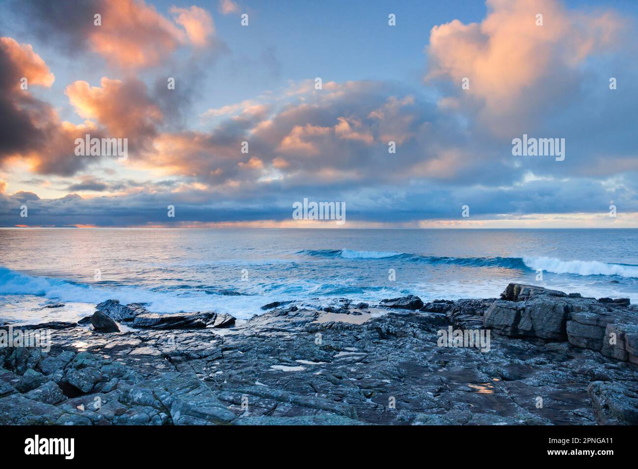 Tief liegende Regenwolken, die über das offene Wasser des blauen Atlantiks bei Sonnenuntergang driften, mit orangefarbenem, wolkigen Himmel, Nordwestküste Schottlands Stockfoto