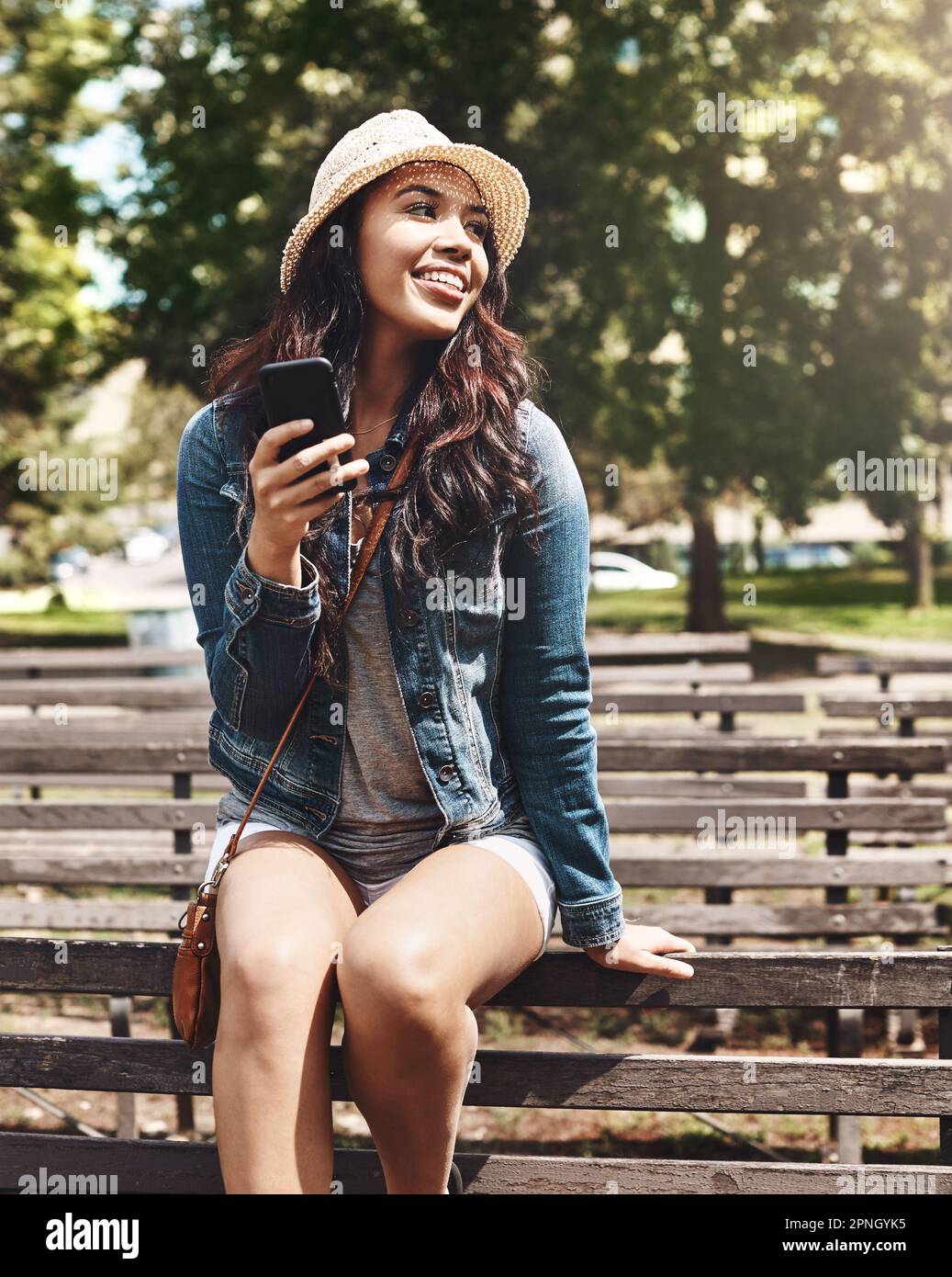 Sag Hallo zum Sommer. Eine attraktive junge Frau, die ein Handy im Park benutzt. Stockfoto