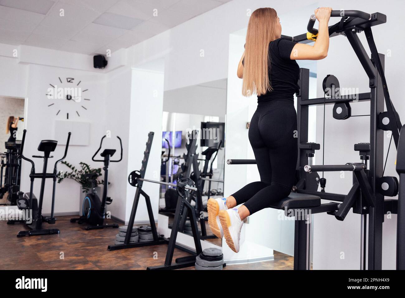 Fit Woman in Sportbekleidung kommt im Sportsimulator an. Sportlerin, die Übungen an Krafttrainingsgeräten macht. Angespannte Sportlerinnen trainieren auf Gravitr Stockfoto