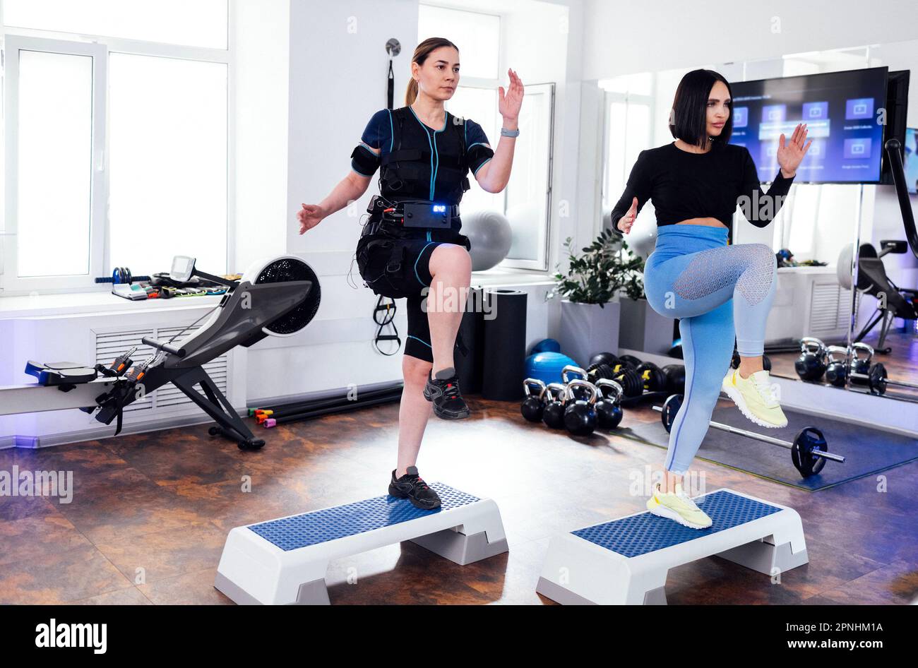 Junge Frau, die mit einem persönlichen Trainer auf der Trittplattform ein rettungstraining macht. Der Coach zeigt die Übung. Frauen im rettungsdienst trainieren mit Stiefeln im Fitnessstudio oder fit Stockfoto