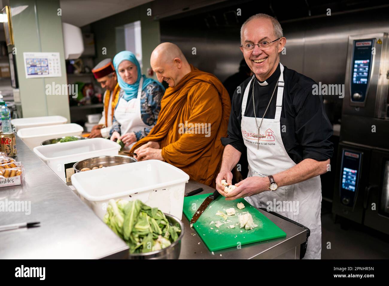 Der Erzbischof von Canterbury Justin Welby (rechts) bereitet Essen zu, während er zusammen mit anderen Glaubensführern an der Big Help Out in The Passage in London teilnimmt, die eine neue Generation von Freiwilligen inspirieren und rekrutieren soll, indem er zeigt, wie einfach es ist, sich einzubringen. Die Veranstaltung mit Glaubensführern und Aktivisten aus den christlichen, jüdischen, muslimischen, hinduistischen und Sikh-Gemeinschaften soll die Menschen ermutigen, am Freiwilligenprojekt Big Help Out am 8. Mai im Rahmen der Feierlichkeiten für die Krönung teilzunehmen. Bilddatum: Mittwoch, 19. April 2023. Stockfoto