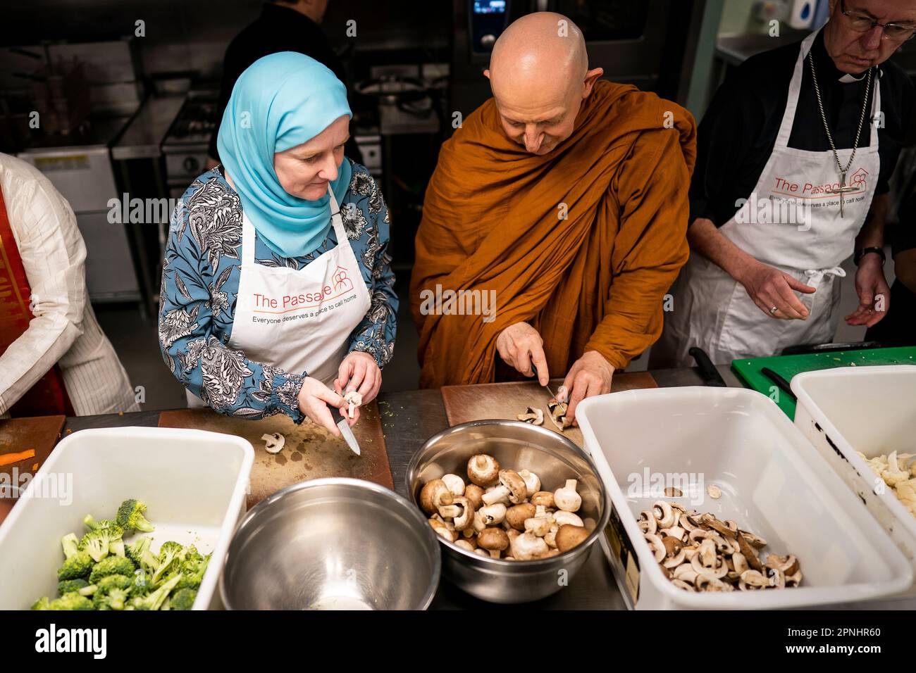 (L bis R) Julie Siddiqi und Venerable Ajahn Amaro bereiten Essen zu, während sie gemeinsam mit anderen Glaubensführern an der Big Help Out in der Passage in London teilnehmen, die eine neue Generation von Freiwilligen inspirieren und rekrutieren soll, indem sie zeigen, wie einfach es ist, sich einzubringen. Die Veranstaltung mit Glaubensführern und Aktivisten aus den christlichen, jüdischen, muslimischen, hinduistischen und Sikh-Gemeinschaften soll die Menschen ermutigen, am Freiwilligenprojekt Big Help Out am 8. Mai im Rahmen der Feierlichkeiten für die Krönung teilzunehmen. Bilddatum: Mittwoch, 19. April 2023. Stockfoto