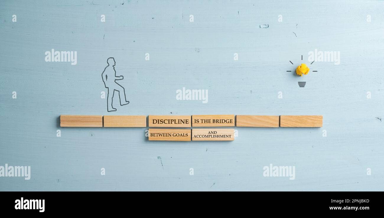 Disziplin ist eine Brücke zwischen Toren und Errungenschaften, die auf einer Brücke aus Holzklammern geschrieben ist. Silhouette eines Mannes, der auf einen zugeht Stockfoto