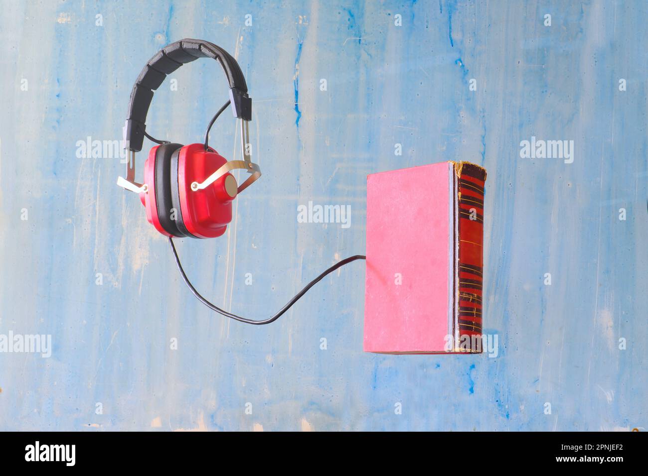 Hörbuchkonzept mit Buch- und Oldtimer-Kopfhörern auf blauem Hintergrund, kostenloser Kopierbereich Stockfoto
