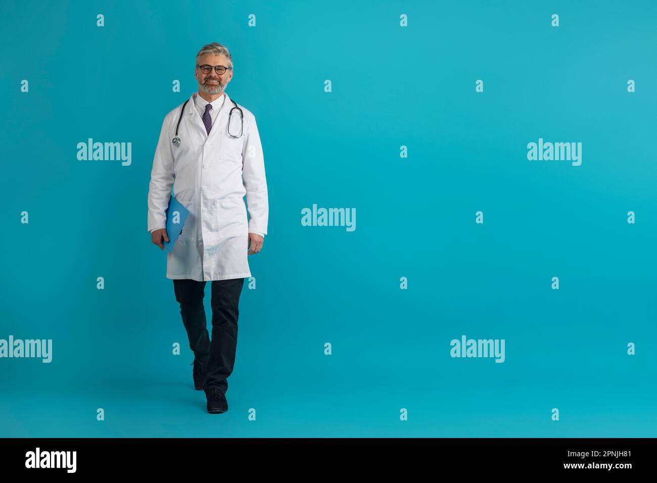 Fröhlicher Arzt mittleren Alters mit Krankenblatt auf blau Stockfoto