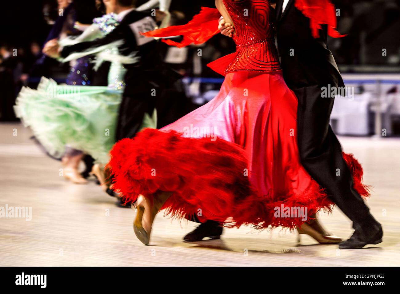 Tanzpaar tanzt Walzer in Wettkampftanz, Frau trägt rotes Kleid und schwarzen Schwanzanzug auf Mann Stockfoto