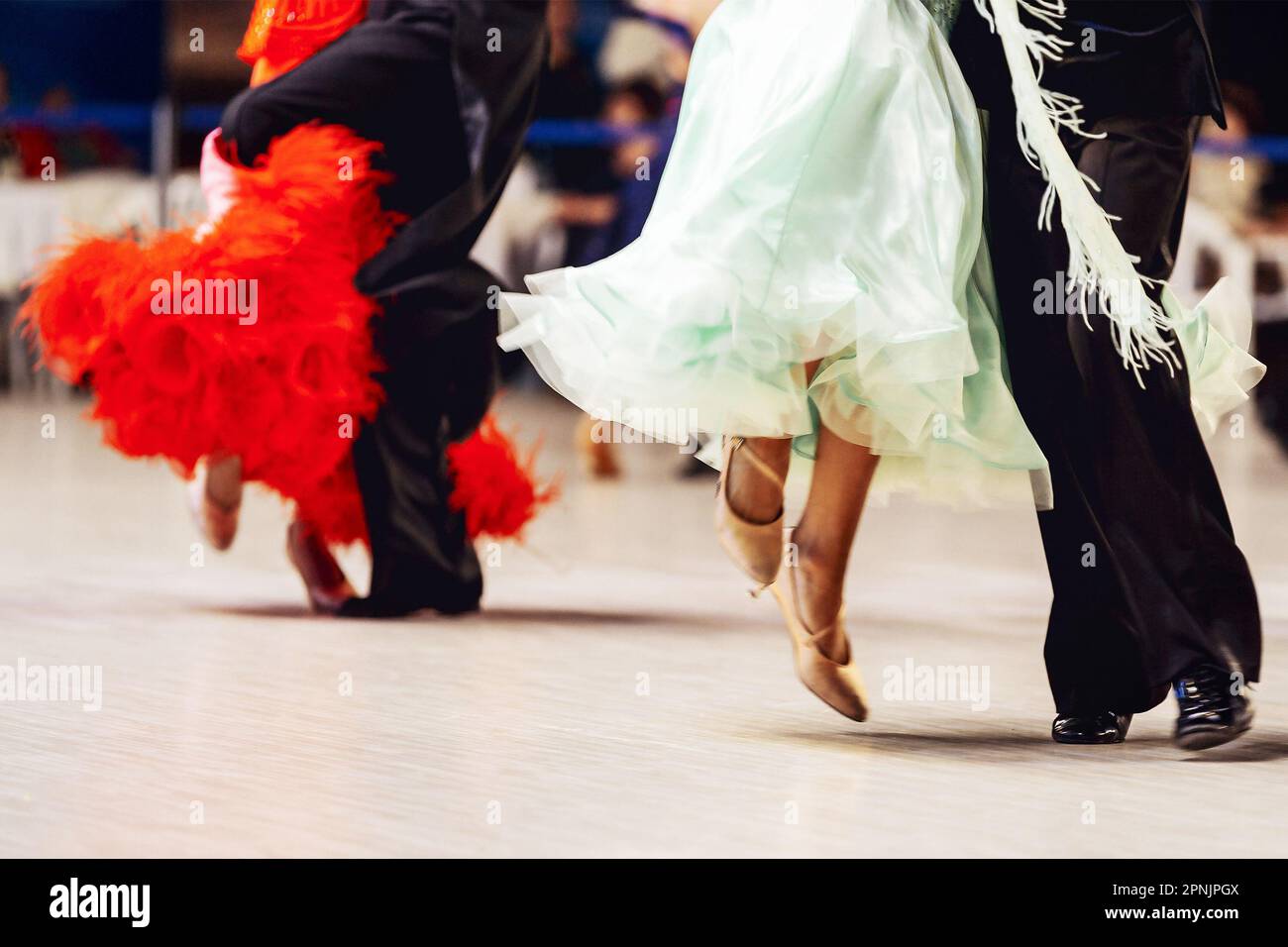 Paare, die wiener Walzer tanzen, im Turnierball tanzen, Frau trägt lila und rotes Kleid, Mann im schwarzen Anzug Stockfoto
