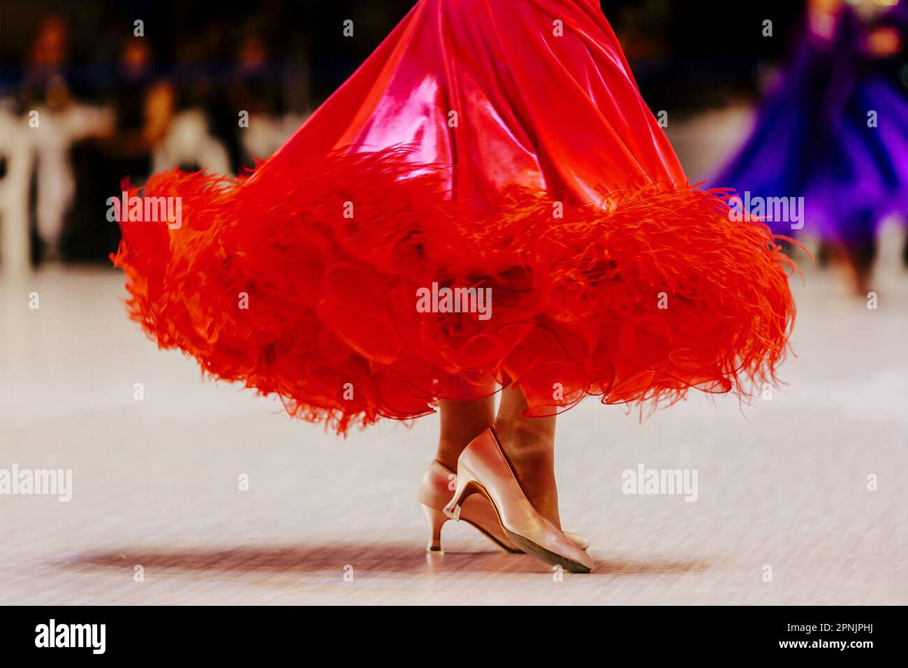 Rotes Ballkleid und Füße im Schuh einer Tänzerin auf Parkett Stockfoto