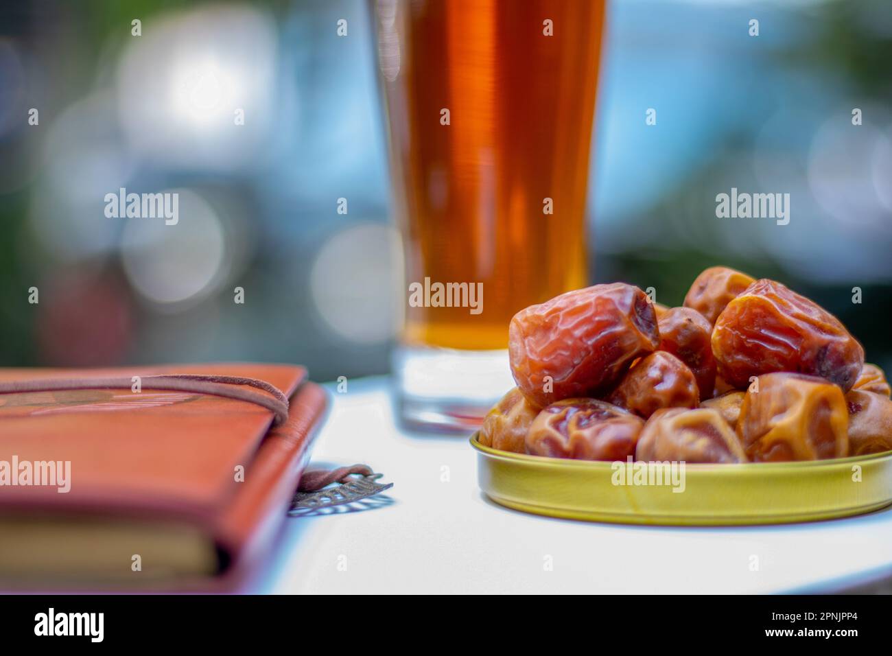 Braune Palmendaten und ein Notizbuch und ein Glas Eistee mit Hintergrundunschärfe. Eine süße Dattelpalme Stockfoto