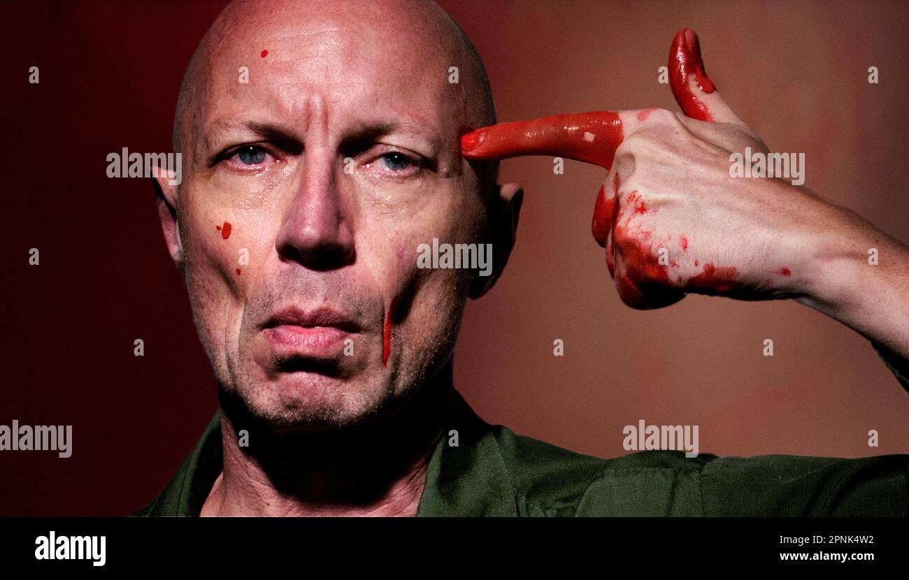 Ein blutiger Mann mit Zeigefinger, der sich wie eine Waffe benimmt und auf seinen Kopf zeigt Stockfoto