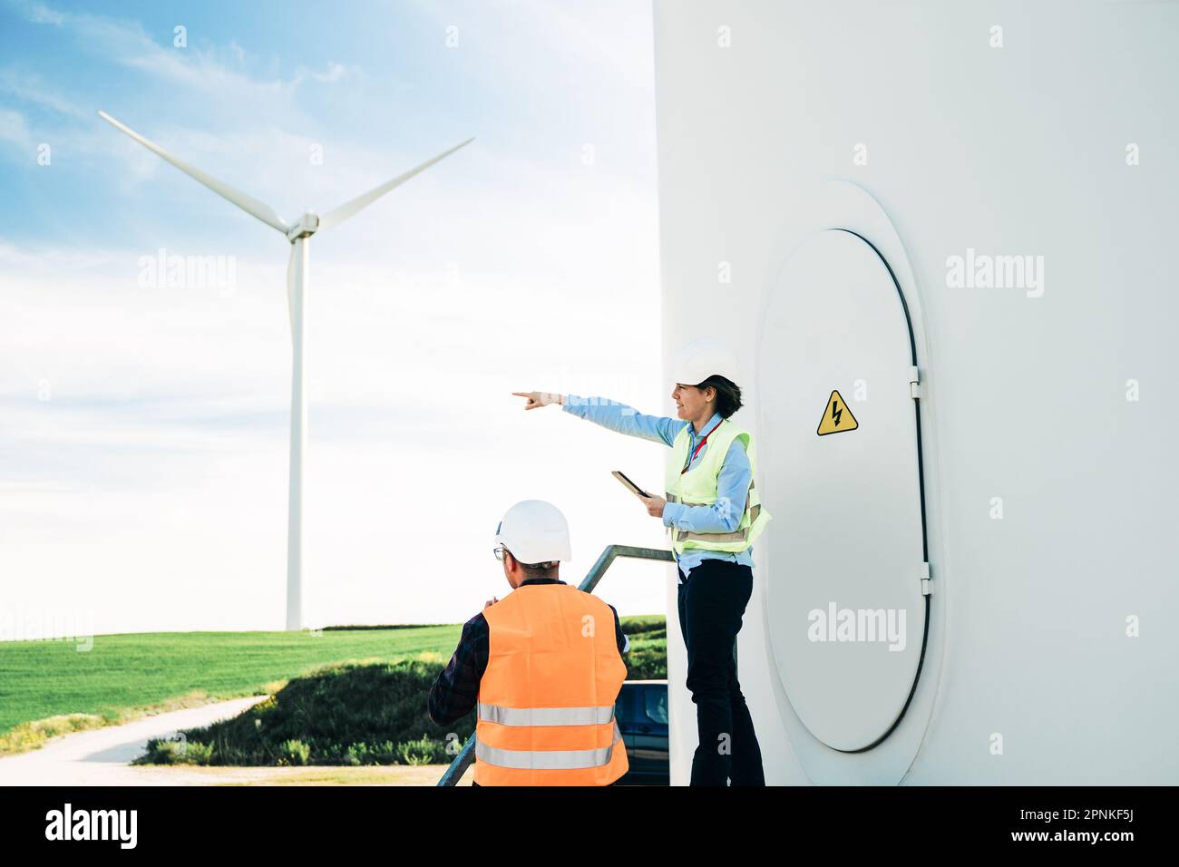 Ingenieure, die im Bereich Innovation, nachhaltige Energiewirtschaft mit Windmühlen im Hintergrund arbeiten – Konzept der umweltfreundlichen Industrie Stockfoto