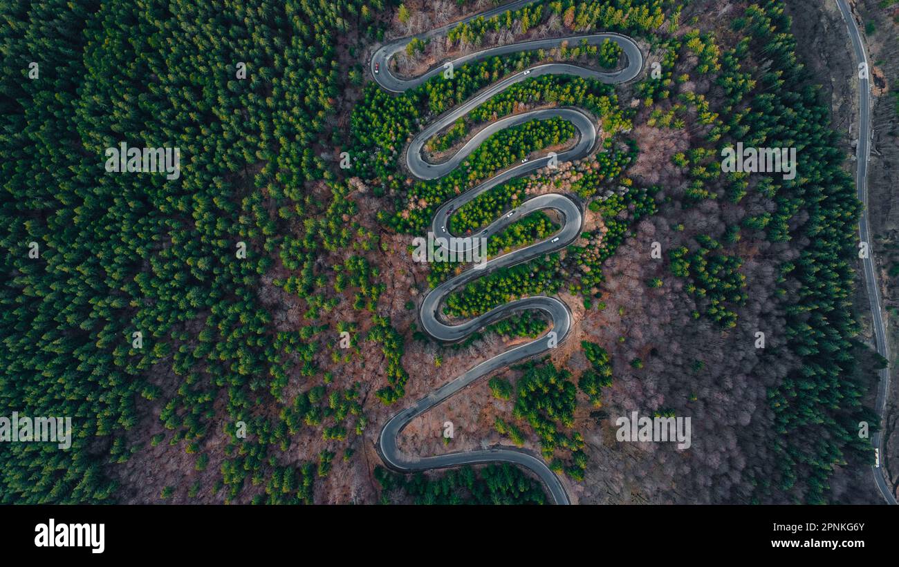 Luftaufnahmen einer gewundenen Straße in den Bergen mit Schlangenlinien und Kurven. Die Fotografie wurde von einer Drohne aus einer höheren Höhe aufgenommen. Stockfoto