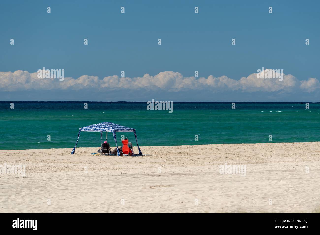 Zwei Personen, die sich unter dem Schatten des Strandes am Kirra Beach, Queensland, Australien, entspannen Stockfoto