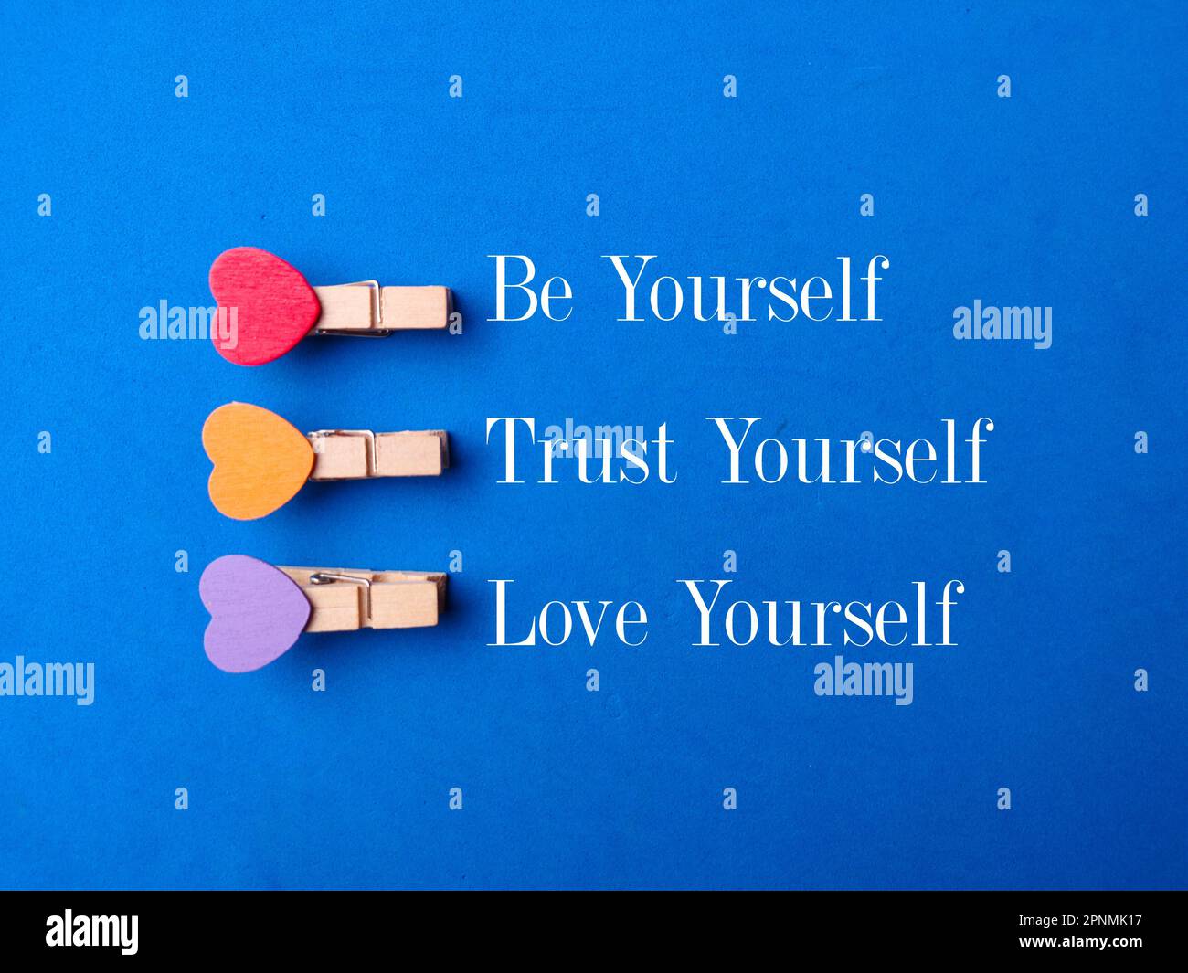 Holzklammern mit dem Wort Be Yourself Trust Yourself Love Yourself auf blauem Hintergrund Stockfoto